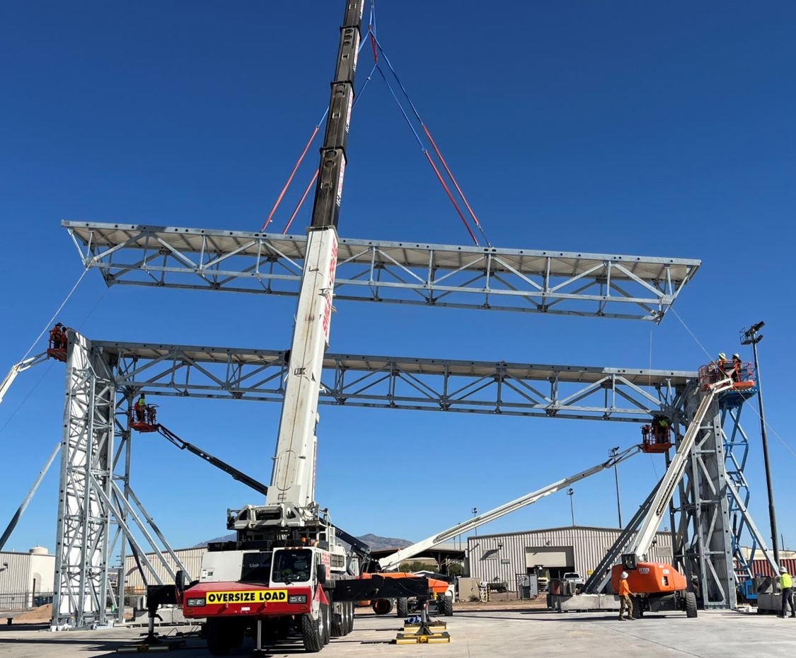 Construction crew lifting a prefabricated steel truss into position.